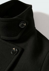 Manteau en mélange de laine noire avec un col haut, un devant double boutonnage et des boutons ronds noirs avec une finition texturée.