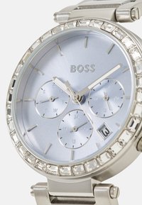 Sølv rustfritt stål klokke med lys blå urskive, tre sub-dials, krystallakkent bezel og datovisning klokken 6.