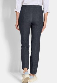 Donkerdenim broeken met een aansluitende pasvorm, met contrasterende verticale stiksels en een middelhoge taille. Gecombineerd met lichte sneakers.