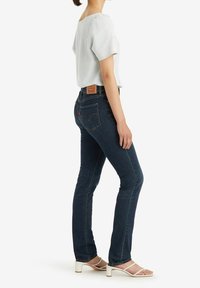 Mörk tvättade denimjeans med slim fit, med en märkesläderpatch på bakfickan och subtila sömnadsdetaljer.