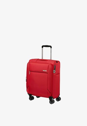 Red soft-shell suitcase with retractable handle, front zip pocket, four double spinner wheels, and side combination lock.