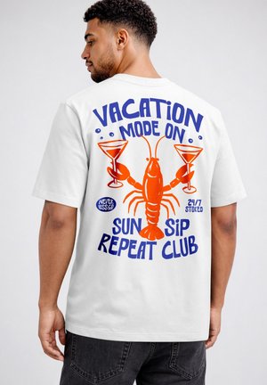 Man wearing white tee shirt with orange lobster holding two cocktail glasses and blue text "Vacation mode on Sun Sip Repeat Club."