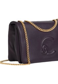 Bolso de mano de cuero morado con logo en relieve y correa de cadena dorada. Presenta una textura suave y diseño doblado. Silueta compacta y elegante.