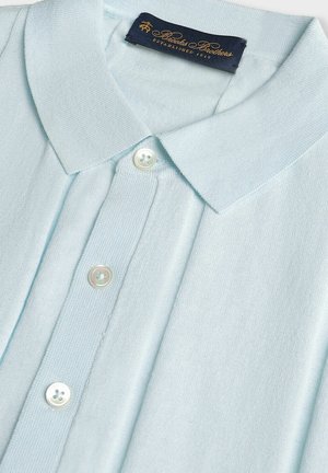 Lichtblau shirt met een polo-kragen van een gestructureerde stof, voorzien van een kraag, drie knopen en een label met de merknaam in gouden letters.