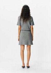Grau gestreiftes Strickoberteil und -rock-Set, kurze Ärmel, tailliert, Oberschenkellänge, strukturierten Stoff, kombiniert mit schwarzen offenen Schuhen.