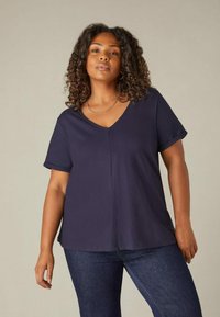 Granatowa koszulka V-neck z krótkimi rękawami i luźnym krojem. Wykonana z miękkiej tkaniny o gładkiej fakturze z dodatkowym szwem na środku.