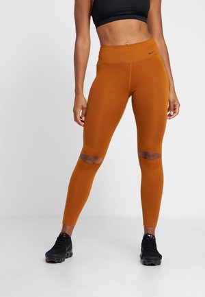 Legginsy Nike w palonym pomarańczowym kolorze, z wysokim stanem, dopasowane do sylwetki, z wycięciami na kolanach. Gładki, elastyczny materiał zapewniający komfort.