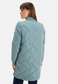 Giacca lunga trapuntata in azzurro chiaro con motivo a diamante, polsini a coste e colletto semplice. Texture liscia e design casual.