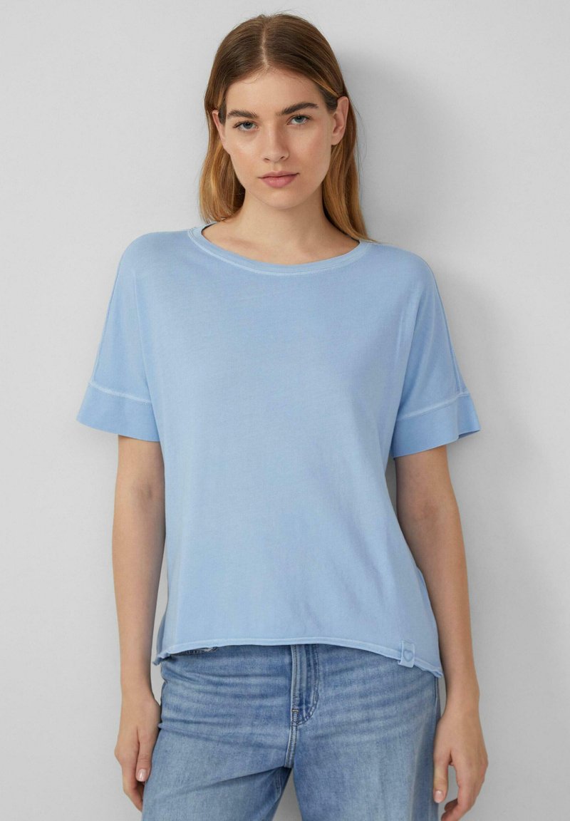 Lichtblauwe top met korte mouwen, gemaakt van zachte stof, met een ronde halslijn en een subtiele zoomaccentdetail. Draag met blauwe jeans.