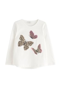 Camicia bianca a maniche lunghe con tre grandi farfalle sulla parte anteriore; una ha una stampa leopardata, mentre le altre due sono a motivi rosa e oro.