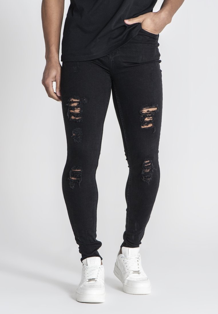 Musta farkkushortsit, joissa on kulutettuja reikiä, tiukka muotoilu ja hieman joustavaa materiaalia. Yhdistettynä valkoisiin lenkkareihin kontrastin luomiseksi.