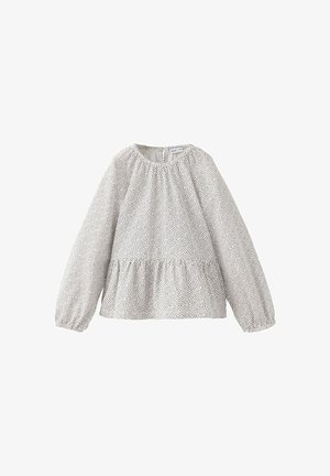 Blouse blanche à manches longues avec petits pois noirs, col rond, coupe ample, poignets élastiques et détail froncé à la taille.