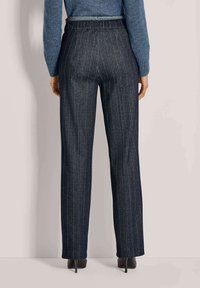 Donkerblauwe pinstripe broeken met een losse fit, elastische tailleband en een lichte textuur. Afgewerkt met een nette zoom en gedragen met hoge hakken.