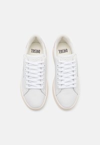 Baskets en cuir blanc avec accents roses, bout rond, lacets plats blancs, semelle extérieure en caoutchouc et doublure intérieure de marque. Design minimaliste.