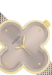 Montre en forme de papillon de couleur or, avec un cadran argenté, des aiguilles fines en or, un bracelet en maille et un design minimaliste.