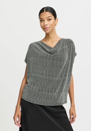 Kurzarmpullover mit V-Ausschnitt aus strukturiertem Schwarz- und Silbergewebe. Drapiertes Design mit subtiler Helligkeit und lockerer Passform, kombiniert mit einem schwarzen Rock.