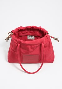 Borsa tote in nylon rosso con cima arricciata, due manici e una toppa rettangolare piatta con logo. Interno foderato in tessuto abbinato, etichetta visibile.