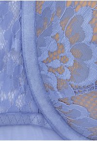 Tessuto in pizzo lavanda chiaro con motivi floreali, bordi in raso e una consistenza semi-trasparente che rivela uno sfondo della tonalità della pelle.