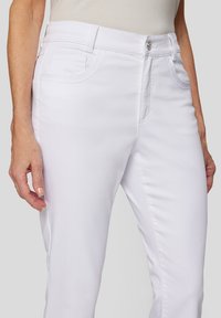 Weiße Jeans im geraden Schnitt mit vorderen und hinteren Taschen, einem Knopfverschluss und subtilen Steppnähten.