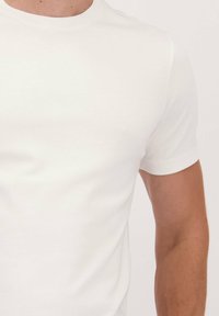 Witte katoenen t-shirt met korte mouwen en een ronde hals. Smooth textuur met een aansluitende pasvorm. Geen zichtbare logo's of patronen.