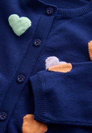 Tamsiai mėlynas megztas kardiganas su dideliais širdies raštais žalia, rožine ir oranžine spalvomis. Apvalus kaklas ir gėlių formos sagos. Minkšta tekstūra.