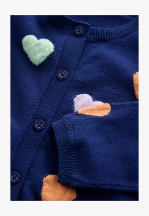 Mornarsko modra pletena jopica z velikimi barvnimi vzorci src v zelenem, roza in oranžnem. Ima okrogel izrez in cvetlične gumbe. Mehka tekstura.