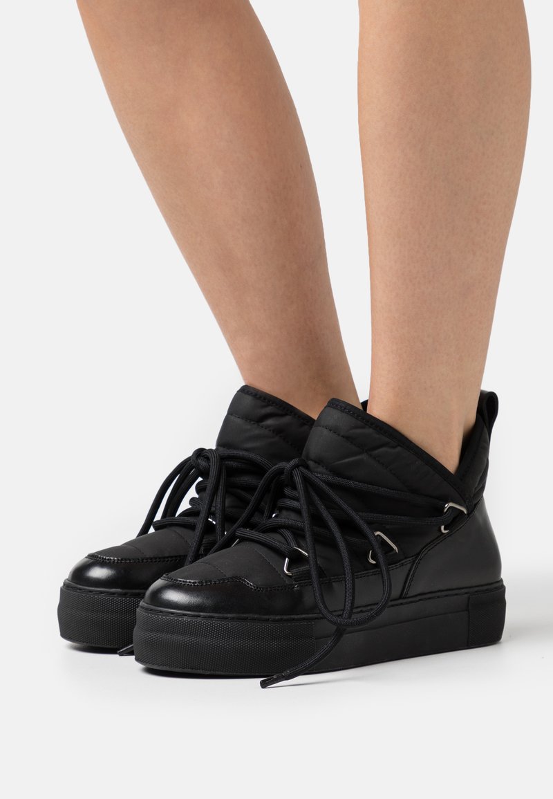 Mustad musta värvi kõrge profili sneaker, millel on tikitud ülemine osa, nahast akandid, ümar varvas ja paks kummist tald. Paelad ja konksud tagavad sobiva istuvuse.