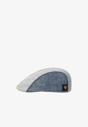 Flat, two-tone flat cap with light gray front and dark blue side panels, featuring a brown round brand logo patch on the side.