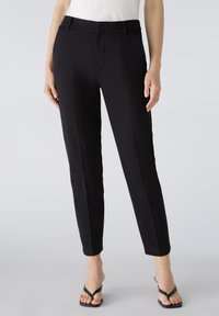 Pantalons noirs ajustés avec une texture lisse, coupe slim et poches latérales. Dotés d'une taille mi-haute et de détails de pli subtils.
