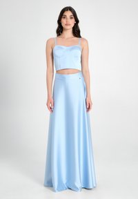 Completo blu chiaro in due pezzi che presenta un top corto aderente con spalline delicate e una gonna maxi fluida in tessuto morbido.