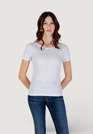 Witte t-shirt met korte mouwen en ronde halslijn, voorzien van een textuur "Eat" logo in zilver. Gecombineerd met donkere, strakke jeans.