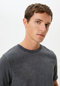 Grå t-shirt med rund hals i et blødt, struktureret stof. Har korte ærmer og ribbet kant ved halsen. Enkelt design uden mønstre.