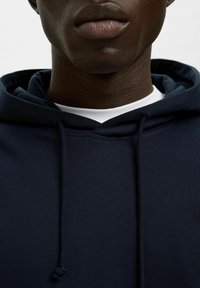 Sudadera azul marino de mezcla de algodón, con capucha ajustable, puños acanalados y una capa interior blanca visible en el cuello.