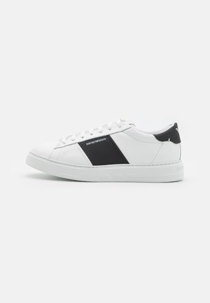 Hvid lav sneakers med sort sidepanel og hælkappe, hvide snørebånd og præget "Emporio Armani" branding på sålen og siden.
