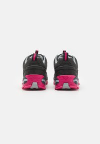 Sorte og grå joggesko med rosa såle og detaljer, med en teksturert overdel og trekkapper på hælen for enkel påkledning.