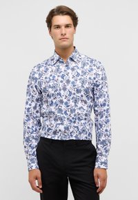 Witte lange mouwen shirt met een blauw bloemenpatroon en accenten in bordeauxrood. De stof lijkt glad met een traditionele kraagontwerp.