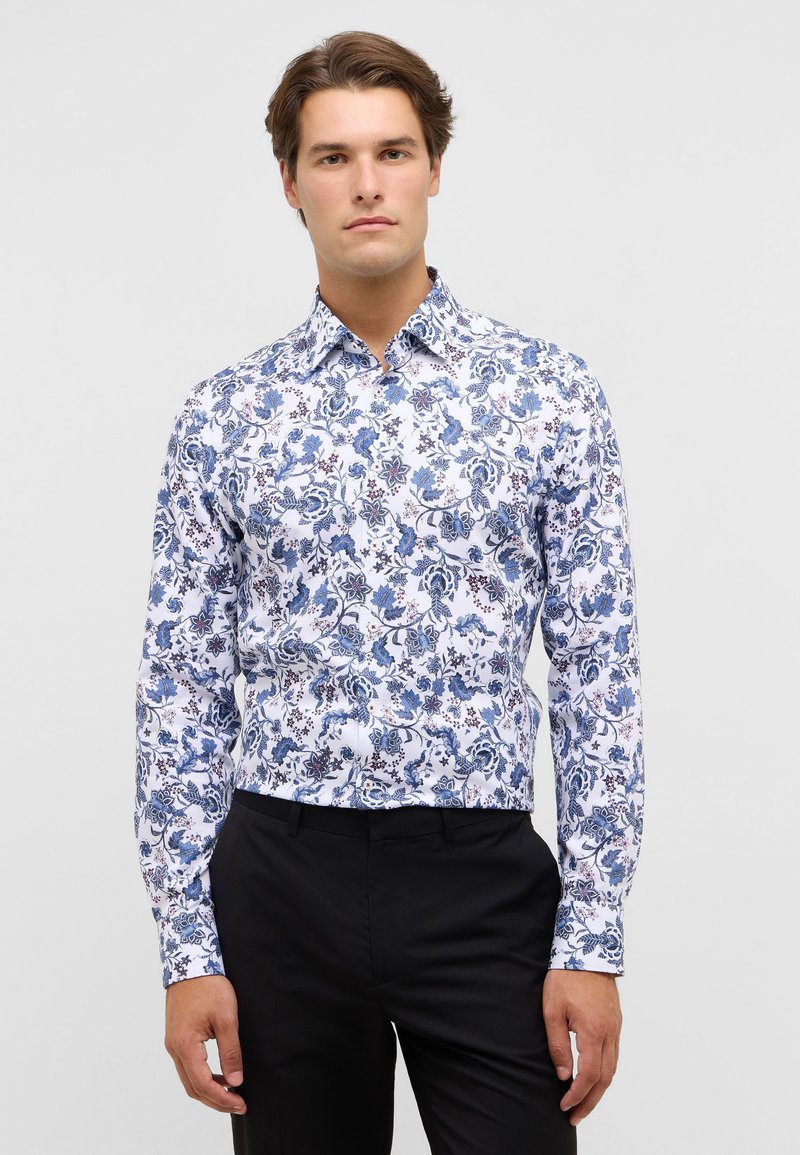 Witte lange mouwen shirt met een blauw bloemenpatroon en accenten in bordeauxrood. De stof lijkt glad met een traditionele kraagontwerp.