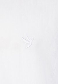 Weißes Baumwoll-T-Shirt mit einem kleinen weißen gestickten Kolibri-Design auf der linken Brustseite. Weicher Stoff, einfacher und minimalistischer Stil.
