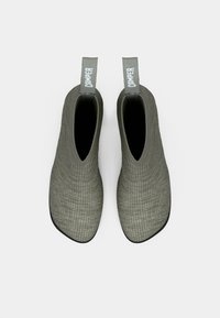 Par de zapatos de punto gris tipo slip-on con suelas negras y tiradores grises etiquetados como "CAMPER", mostrados desde arriba sobre un fondo blanco.