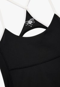 Musta urheilullinen hihaton paita valkoisilla olkaimilla, koko medium, jossa on "Koton Sport" -logo ja valmistettu Turkissa -merkki sisällä.