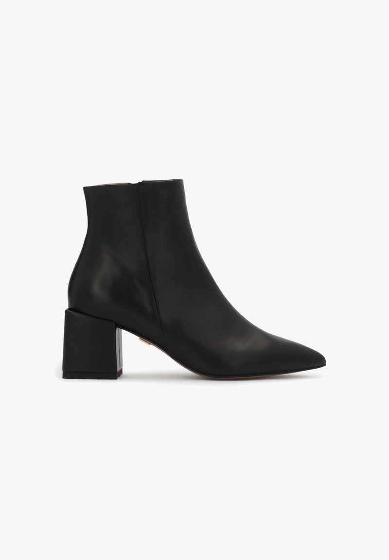 Bottine en cuir noir avec bout pointu et talon bloc, fermeture éclair latérale, finition lisse, sur fond blanc.
