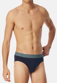 Navy-Boxershorts mit einem grauen elastischen Taillenband, das das "SCHIESSER"-Logo trägt. Glattes Material, enganliegendes Design mit klassischer Unterhosenform.