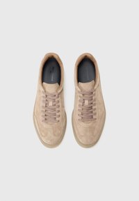 Paire de baskets en daim beige avec lacets assortis, bouts arrondis et semelles intérieures noires sur fond gris clair.