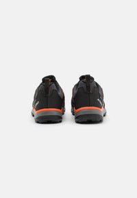 Chaussures de randonnée noires avec des accents orange, tige en mesh, col rembourré et semelle en caoutchouc texturé, dotées d'une languette au talon pour un enfilage facile.