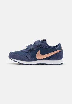 Børns mørkeblå sneakers med rosaguld Nike swoosh, to velcrobånd og hvid sål, set fra siden på en ensartet lys baggrund.