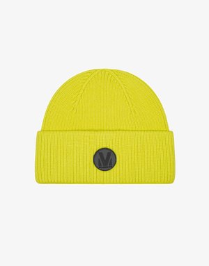 Dzeltena adīta cepure ar ribotu tekstūru, salocīts malā, un melnu apļa logotipa uzlīmi. Vienkārša apaļa forma, izgatavota no mīksta materiāla.