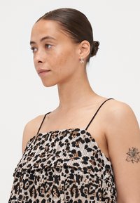 Dierprint top met geplooid design in beige, zwart en bruin. Bevat dunne zwarte banden en gelaagde ruches voor extra textuur.