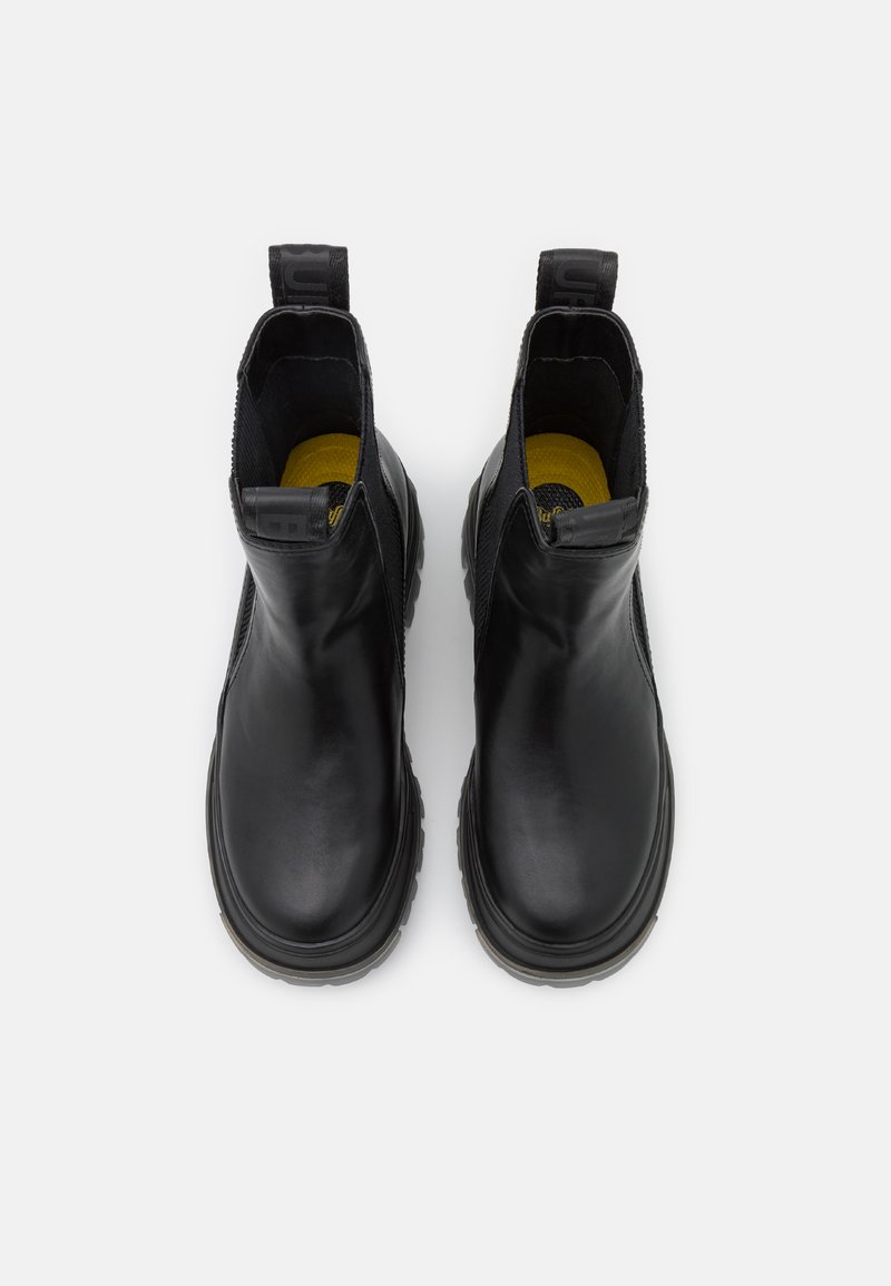 Schwarze Leder-Stiefeletten mit glatter Textur, elastischen seitlichen Einsätzen und Gummisohlen. Hervorhebung ist die gelbe Innensohle und der Zugschlaufe hinten.