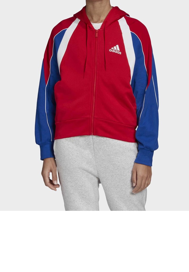 Sudadera con cremallera roja y azul con acentos blancos, fabricada en material suave, con capucha y puños acanalados. Logo de Adidas en el pecho.