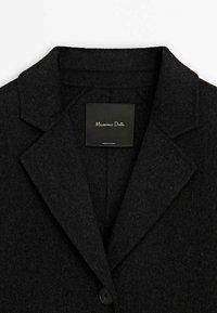 Col et revers de blazer en laine noire texturée avec un seul bouton et étiquette Massimo Dutti cousue à l'intérieur du cou.